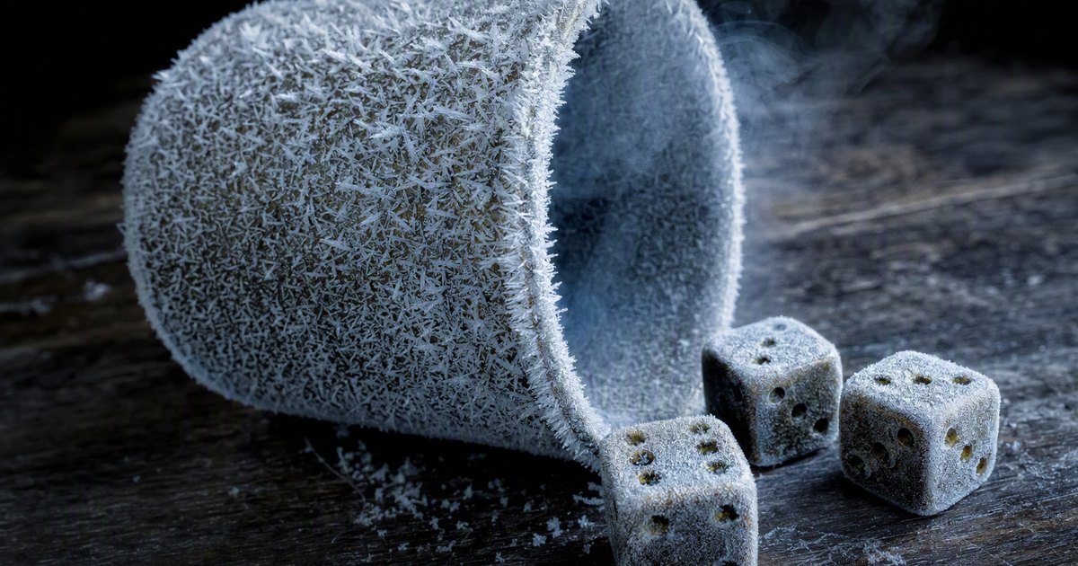 A brass dice cup covered in thick frost stands on a dark table. Frosted dice lie beside it showing different numbers
